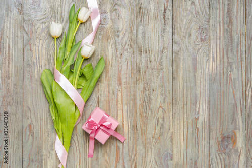 Gift and beautiful flowers on wooden background