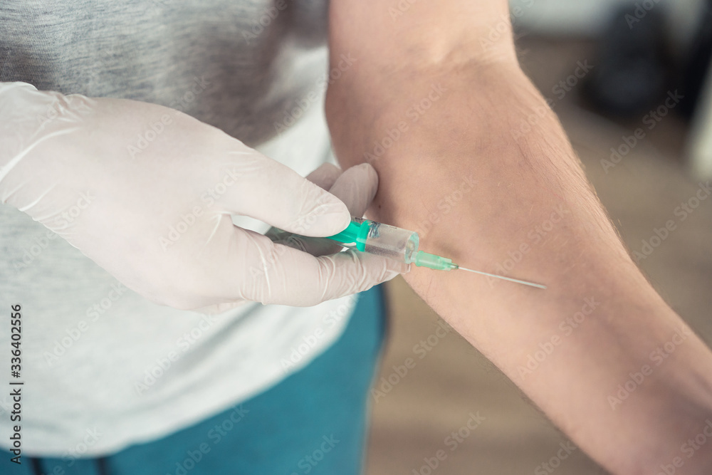 hand in medical gloves with a syringe on a light background hand in medical gloves with a syringe on a light background