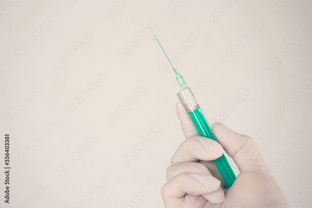 hand in medical gloves with a syringe on a light background hand in medical gloves with a syringe on a light background