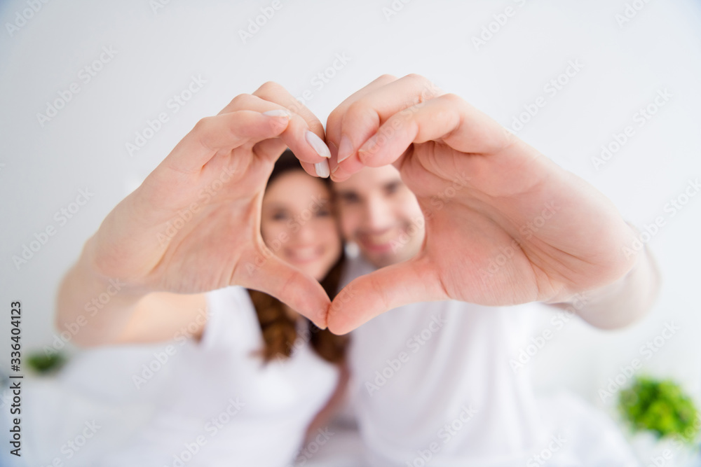 Closeup blurry focus photo of adorable lady handsome guy married couple together overjoyed hold hands making heart figure gesture symbolizing cardiac feelings wear pajama room indoors Closeup blurry focus photo of adorable lady handsome guy married couple together overjoyed hold hands making heart figure gesture symbolizing cardiac feelings wear pajama room indoors