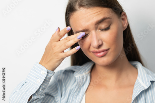 Quadro su tela Girl Touching Eyes Having Conjunctivitis Standing On White Studio Background