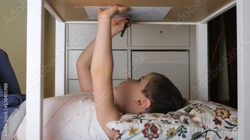 Boy painting upside down. Leisure activity at home, indoor. Preschooler drawing lying under the table. Little painter drawing carefully his painting. Preschool age. Exciting learning. Think different