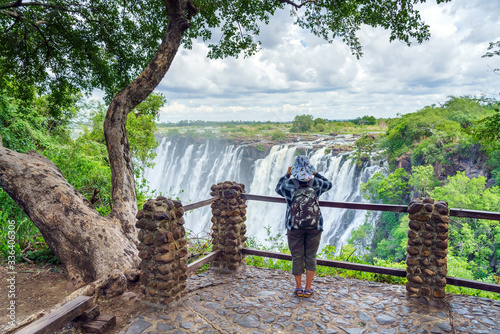 View of a tourist at the dramatic waterfall and clouds at Victoria Falls, Zimbabwe, Zambia. photo