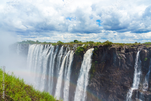 Panorama view with dramatic clouds and waterfall at Victoria Falls on the Zambezi River  Zimbabwe  Zambia.