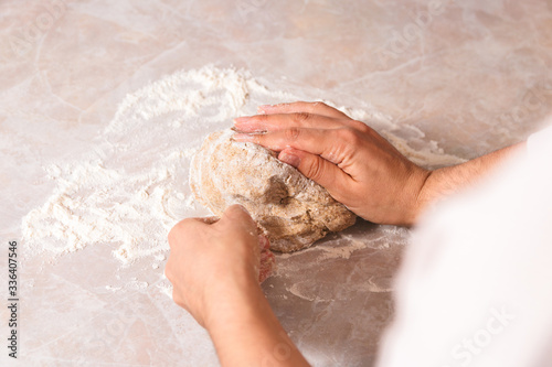 process of baking health bread at home. closeup woman hands kneading dough from rye flour on marble countertop in bright kitchen