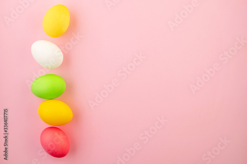 Beautiful easter eggs painted in yellow, red and green pastel colors on a pink background.