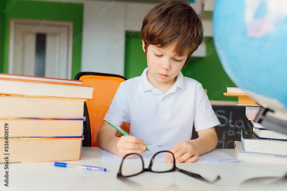 Stay at home, online learning, distance learning, self quarantine concept. Boy start doing homework with books notebooks for lesson at home Stay at home, online learning, distance learning, self quarantine concept. Boy start doing homework with books notebooks for lesson at home