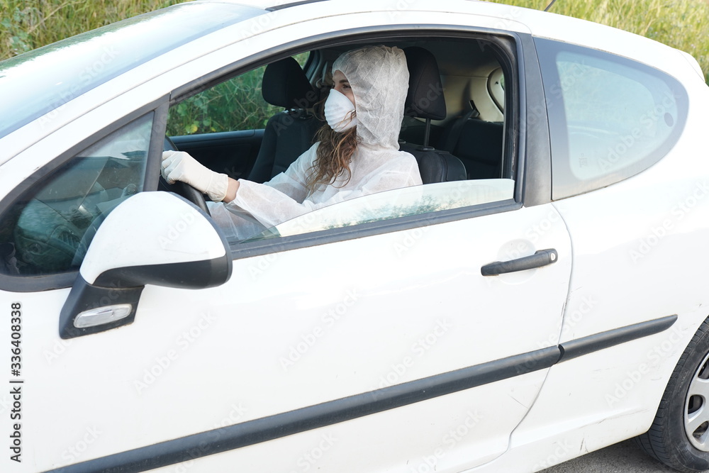Dressed in full protective gear mask driver collects a sample from a man sitting inside his car as part of the operations of a coronavirus test
