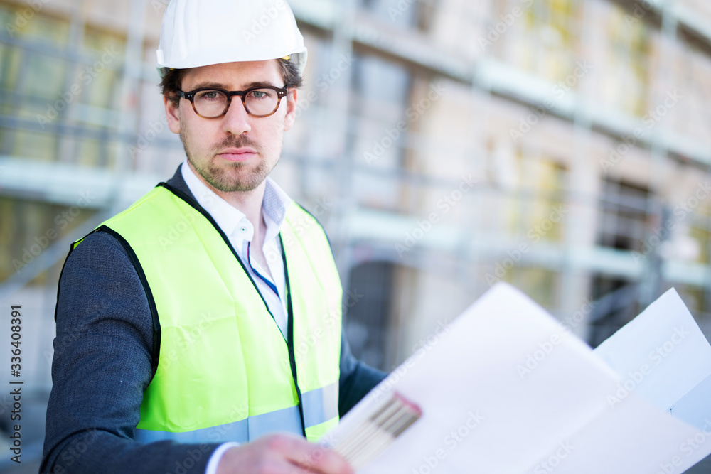 Mann im Anzug mit Helm und Weste auf einer Baustelle Mann im Anzug mit Helm und Weste auf einer Baustelle