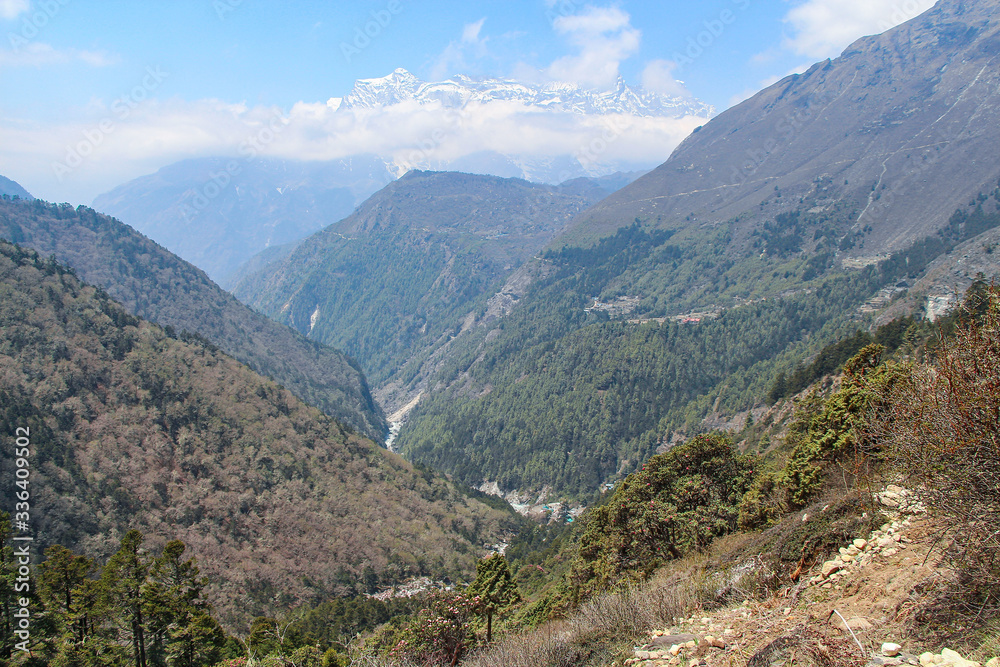 Beautiful mountain valley with flowing river in Himalayas in the day. Kongde Ri mountain in the background. Mountainside is covered by forest. Beautiful landscape. Theme of travel in Nepal.