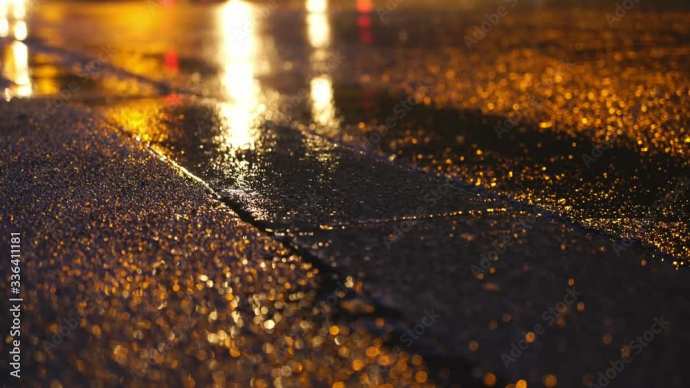 Bright headlights and street lights reflection on night city street after rain 