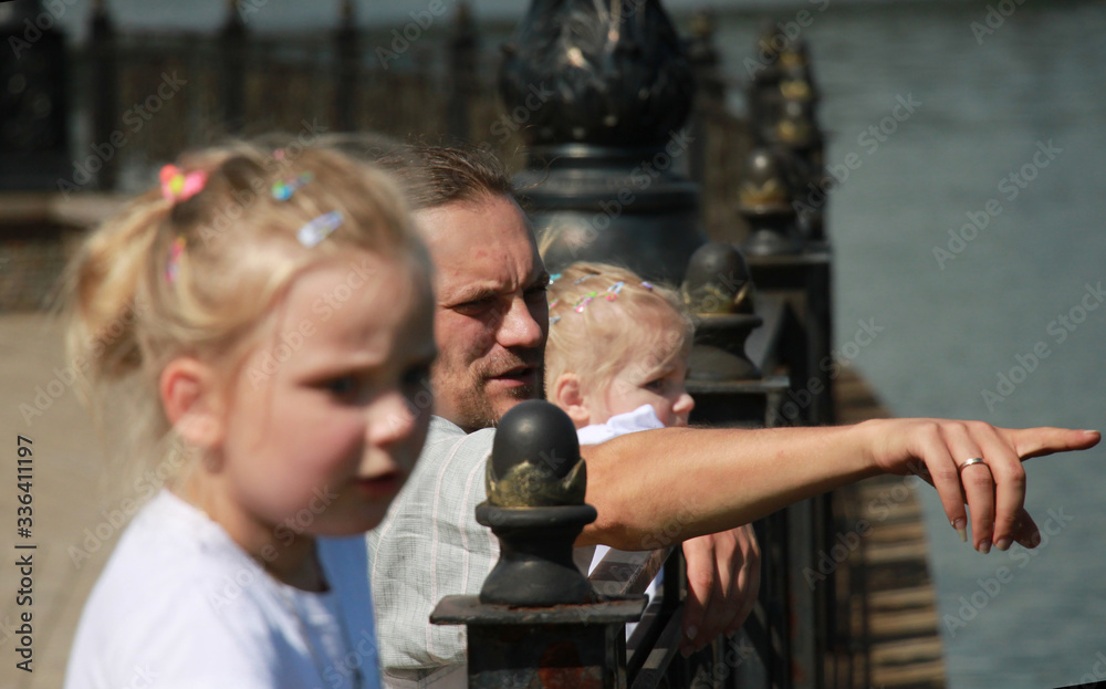 dad with two daughters look over the railing at the water