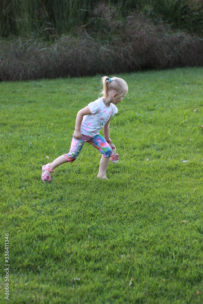 girl runs on grass in one sandal