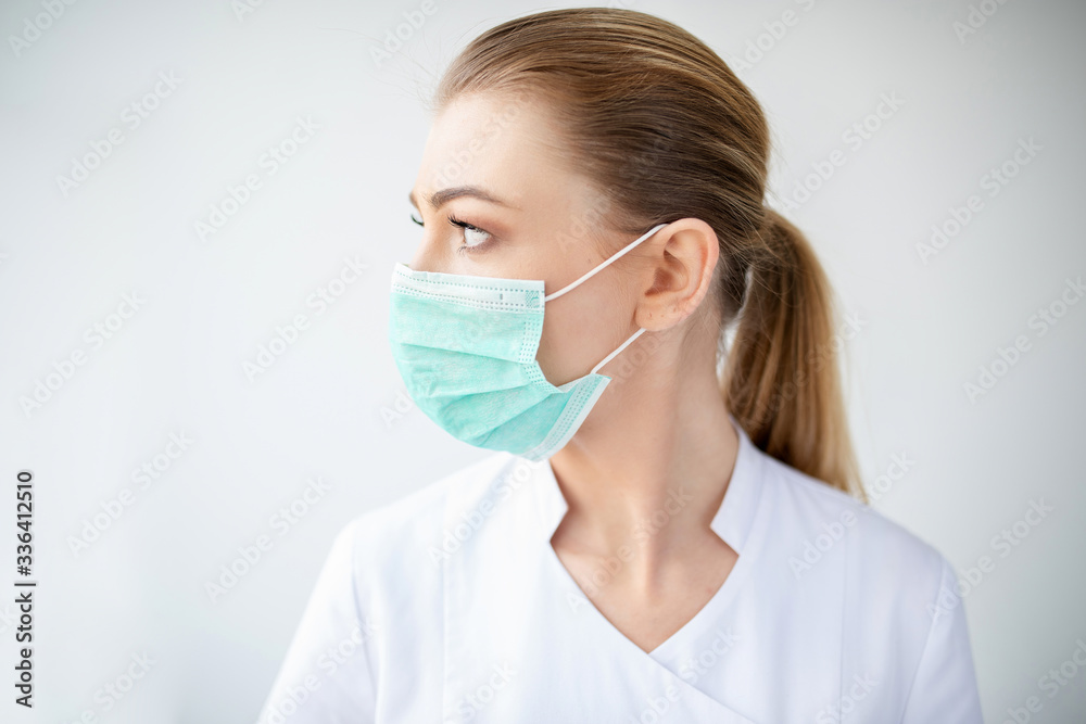 Female doctor in medical attire, protective mask tired in depression in hospital by the window Female doctor in medical attire, protective mask tired in depression in hospital by the window