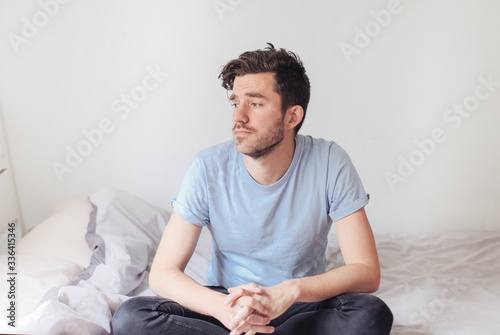 Man looking bored and sad staying at home in bed