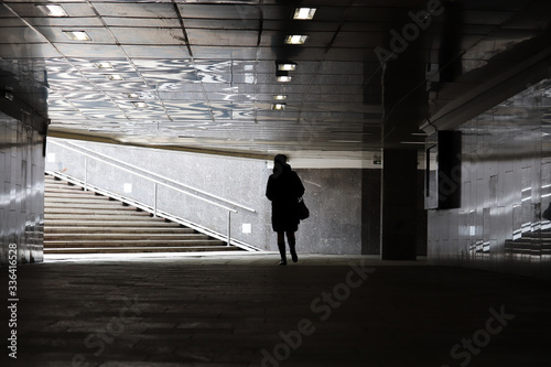 Quarantine in the city during the Covid-19 coronavirus pandemic. Silhouette of woman walking in empty underpass in Moscow