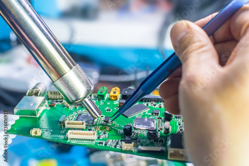Obraz na płótnie Technical support worker drops the fee PCB. Soldering iron. Tweezers