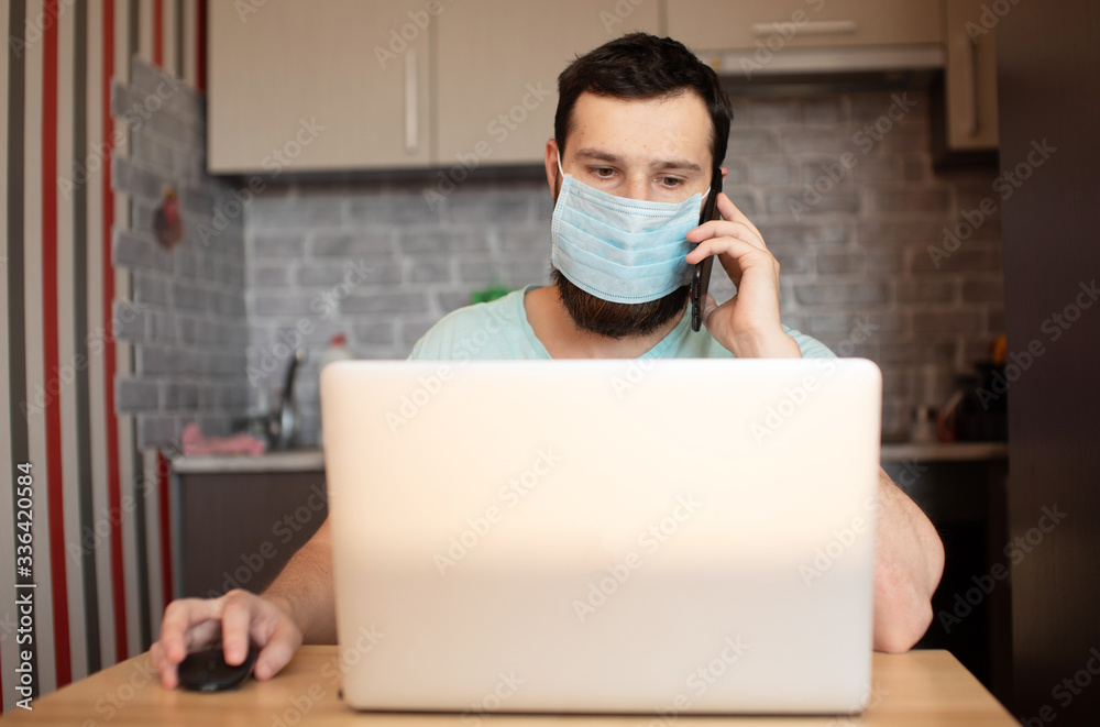 Bearded man with protective face mask working home due quarantine coronavirus covid-19 infection pandemic. Young man with laptop at remote job staying home. Bearded man with protective face mask working home due quarantine coronavirus covid-19 infection pandemic. Young man with laptop at remote job staying home.