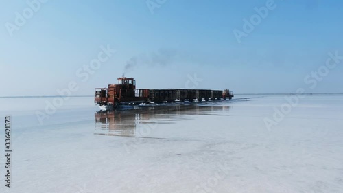 Old train rides on the railway laid in the water through the salt lake. train travels from water. Mined salt in Lake Burlin. Altai. Bursol. Russia. August 2019 