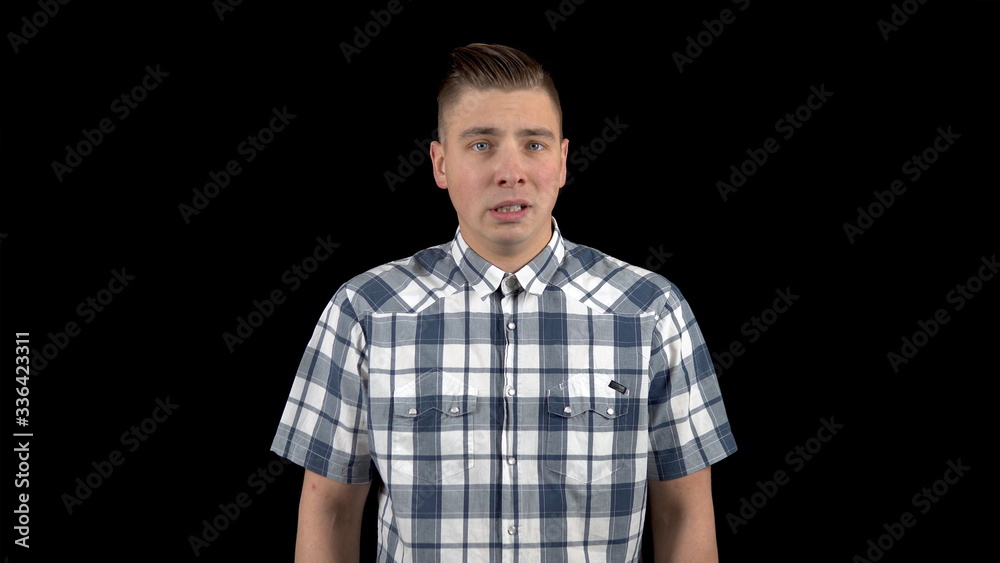 A young man shows an emotion of fear on his face. A person experiences fear. A man in a shirt on a black background A young man shows an emotion of fear on his face. A person experiences fear. A man in a shirt on a black background