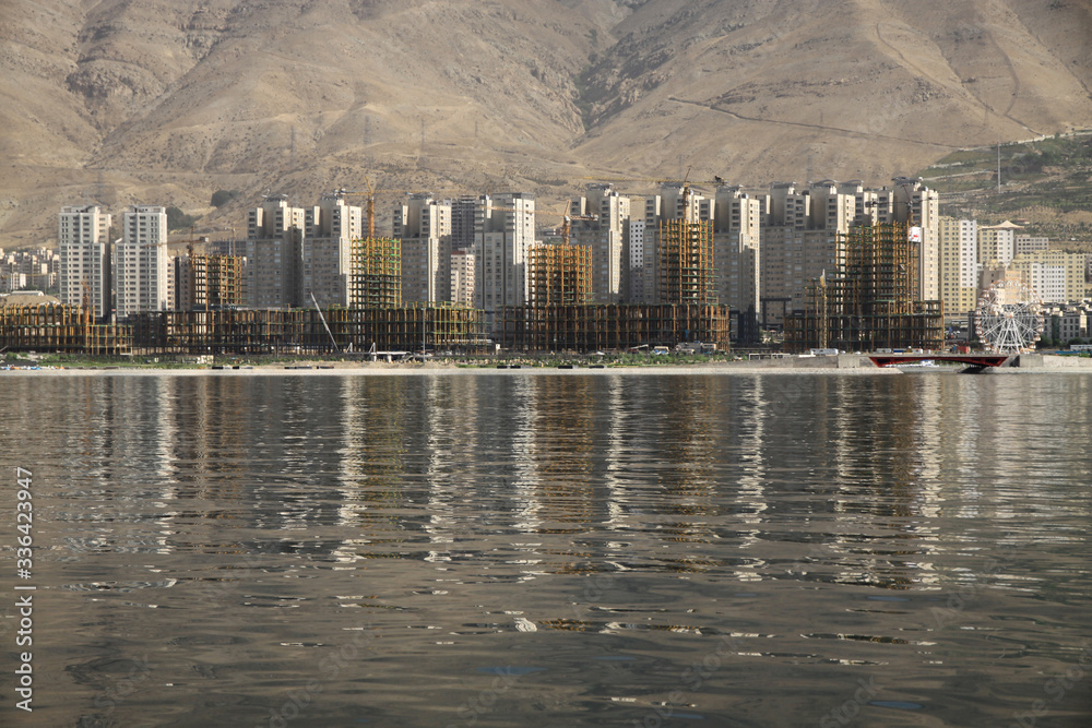 osiedle apartamentowców położone nad jeziorem w górach w iranie - obrazy, fototapety, plakaty 