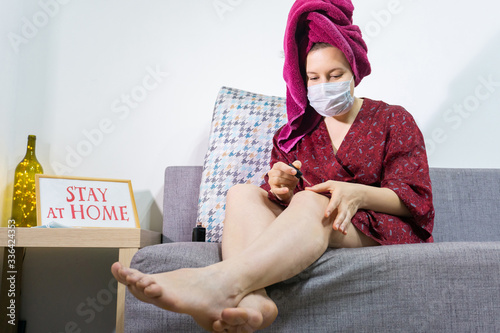 Young woman relaxing at home and paint nails. Cozy time at home. Self time and Coronavirus outbreak quarantin concept. photo