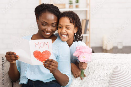 Leinwand Poster Black girl congratulating her mom with flowers and card