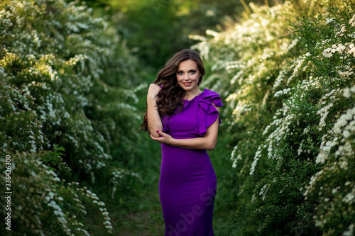 beautiful young girl in a purple dress in bloom of white flowers, photo shoot of a girl,