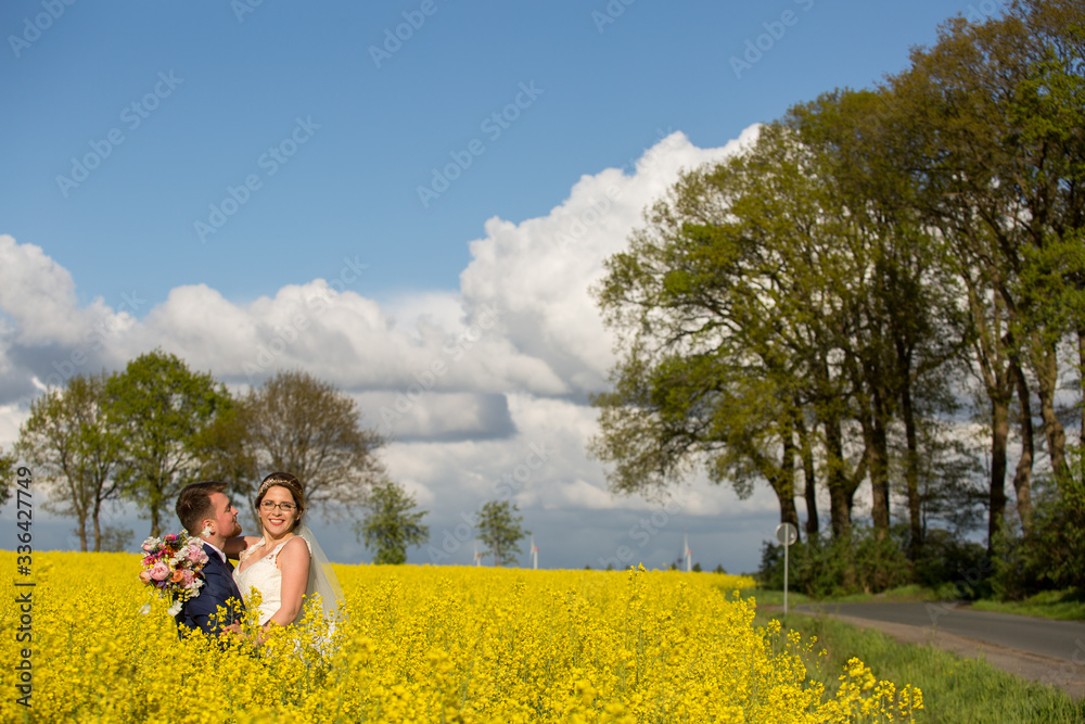 Beautiful young wedding couple posing outdoor in yellow field
