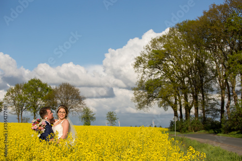 Beautiful young wedding couple posing outdoor in yellow field