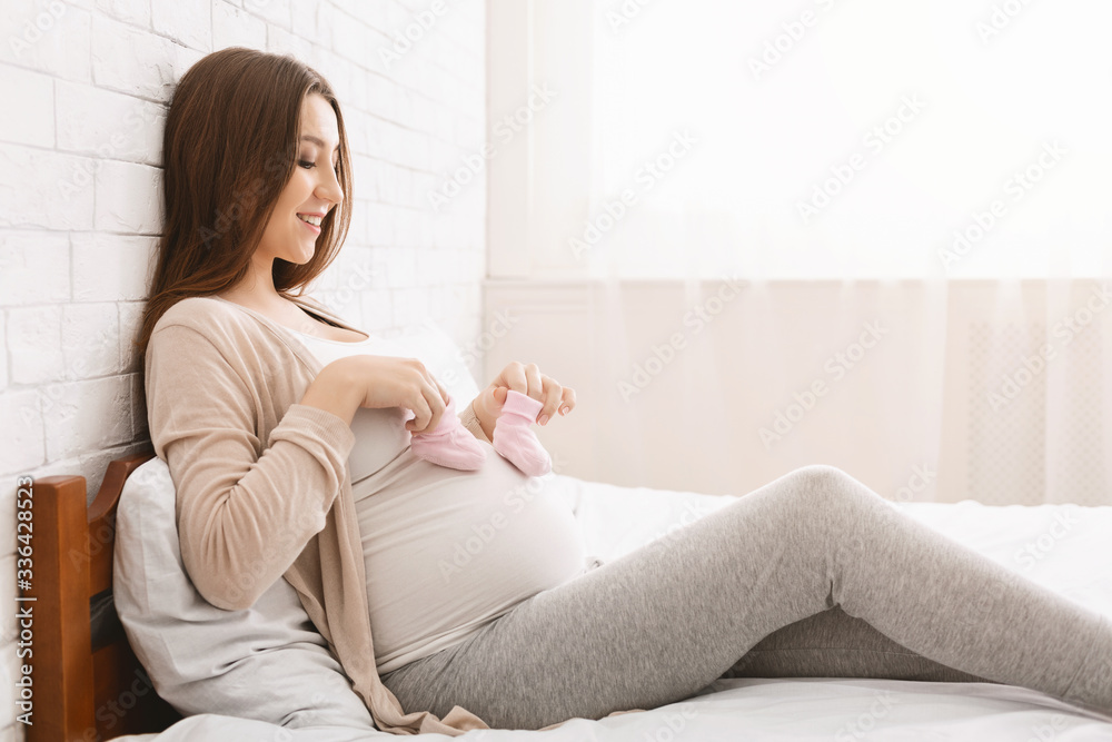 Pregnant woman playing with tiny shoes, stepping on belly Pregnant woman playing with tiny shoes, stepping on belly