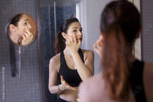Donna si mette il contorno occhi davanti allo specchio nel suo bagno photo