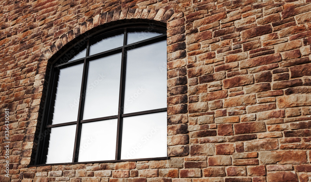 large arch-shaped window with reflective glass and a binding on a stone ...