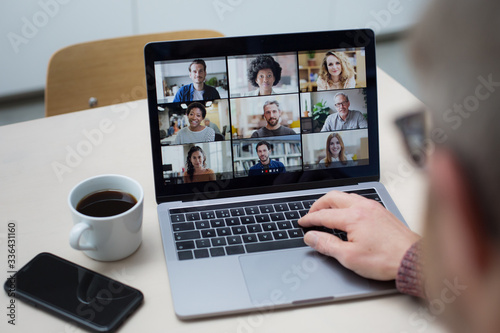 Person Using Video Conferencing technology in kitchen for video call with colleagues at home and in offices photo