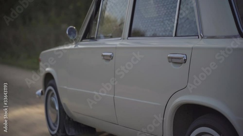 Old white soviet vintage car driving on dirt road
