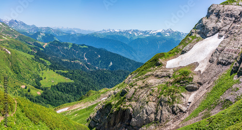 Fototapeta Naklejka Na Ścianę i Meble -  View over the Green Valley, surrounded by high mountains with snow on a clear summer day.
