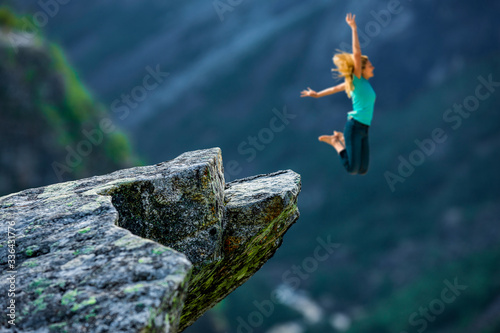 Frau springt im Gebirge von einem Fels