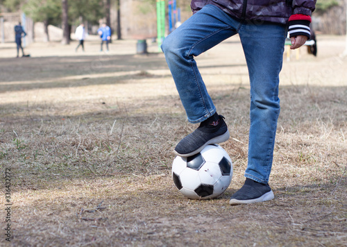 a boy in a red hood plays soccer with a soccer ball on the street