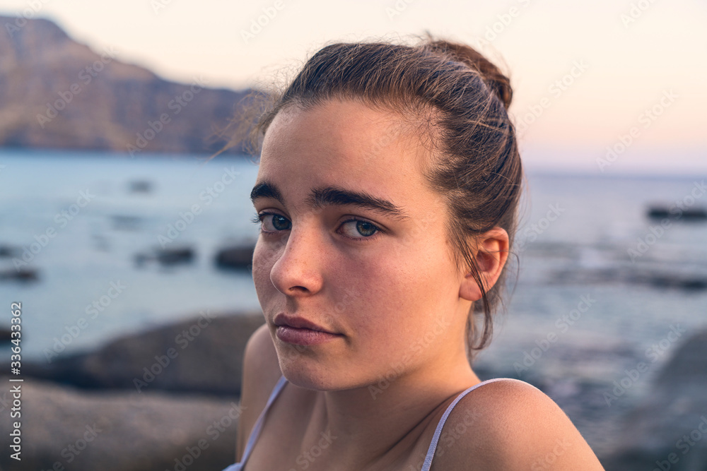 Portrait of a young woman by the sea in the evening sun