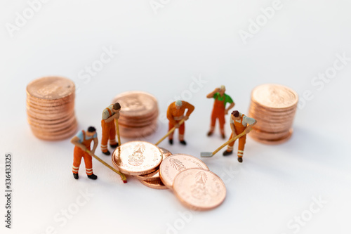 Miniature people: Worker working on stack of coins, income from work. Image use for business concept.