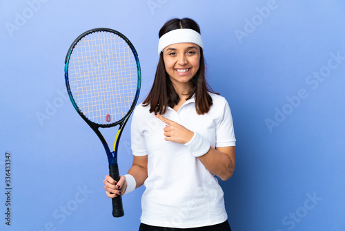 Young woman tennis player over isolated background pointing to the side to present a product