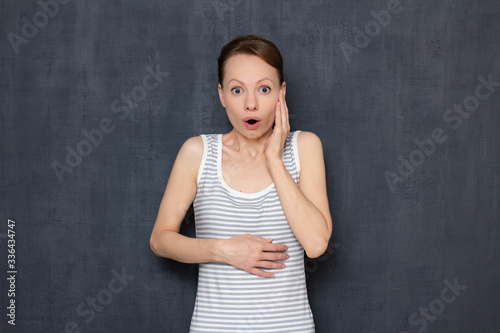 Studio portrait of shocked woman with widened eyes and open mouth