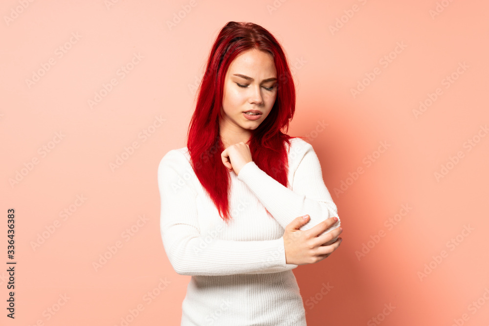 Teenager red hair girl isolated on pink background with pain in elbow Teenager red hair girl isolated on pink background with pain in elbow
