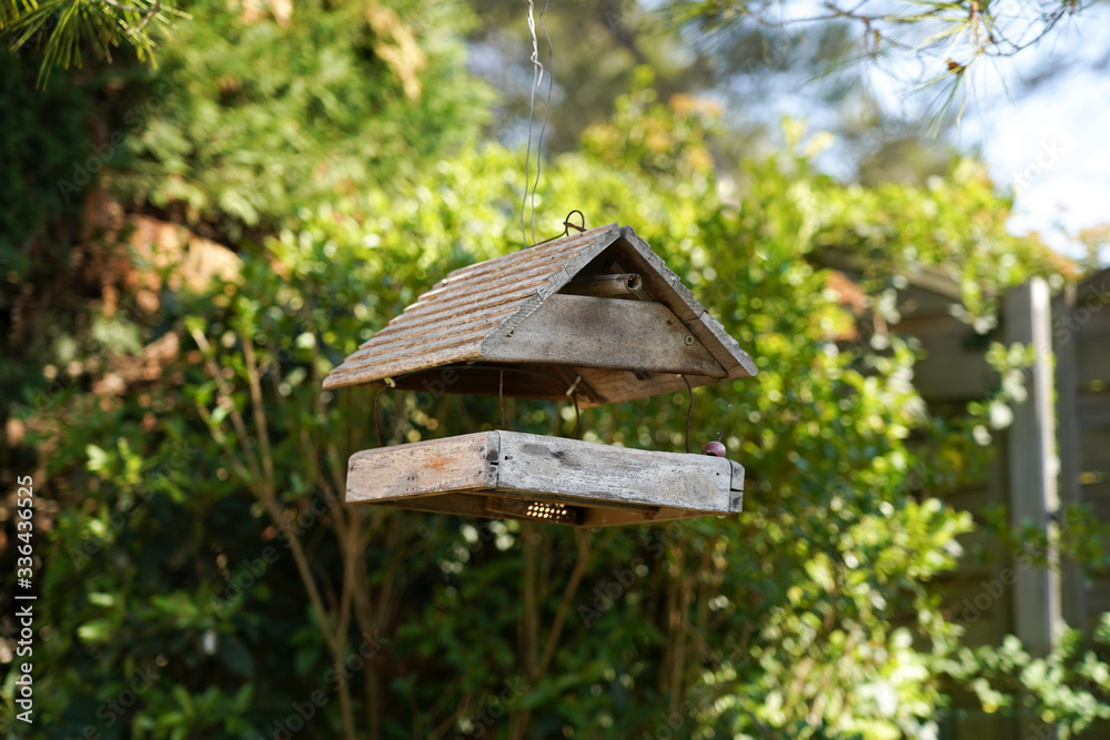 Mangeoire à oiseaux en bois suspendue à un pin sur fond de nature Mangeoire à oiseaux en bois suspendue à un pin sur fond de nature