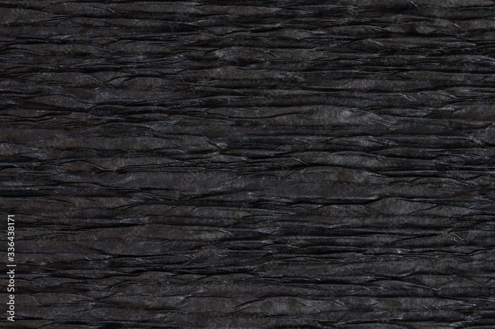 Background of black pressed corrugated paper with a horizontal texture taken close up Background of black pressed corrugated paper with a horizontal texture taken close up