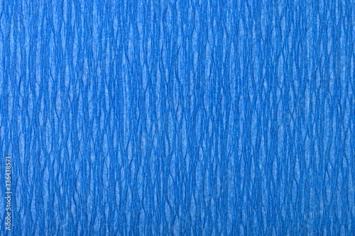 Background of blue pressed corrugated paper with vertical texture taken close up