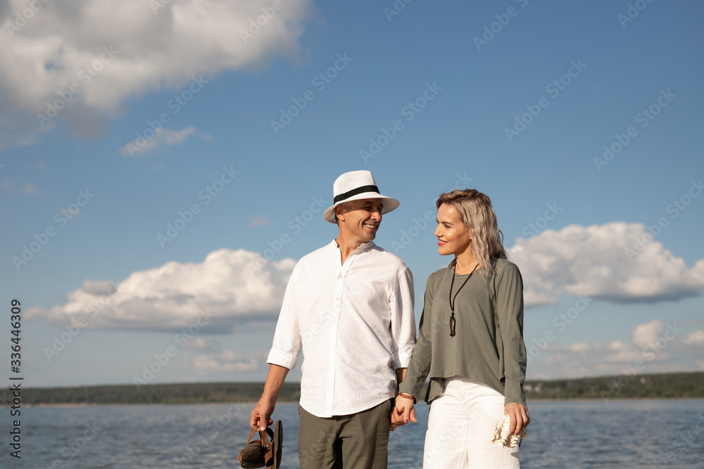 Woman and man walk on the beach in sunny weather