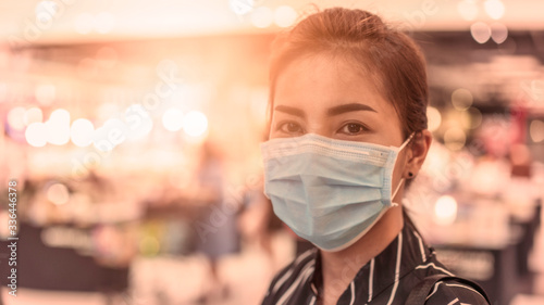 Selective focus on the eyes, Asian woman wears protective mask to protect against Coronavirus 19, Beautiful bokeh background with soft orange light, The concept of virus protection and self-belief.