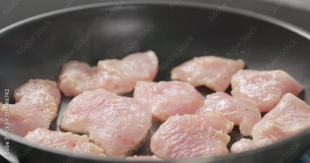 Slow motion shot of turkey fillet pieces frying on nonstick pan Slow motion shot of turkey fillet pieces frying on nonstick pan