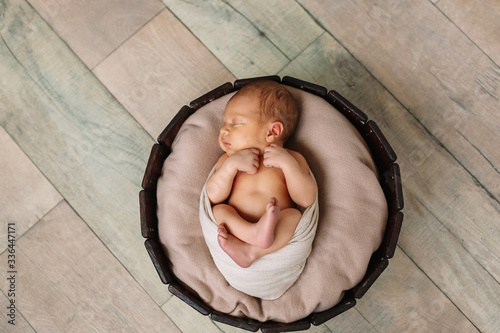 
Newborn baby boy, in the photo the baby is 7 days old from birth, wrapped in a wrapping, sleeps sweetly in a basket